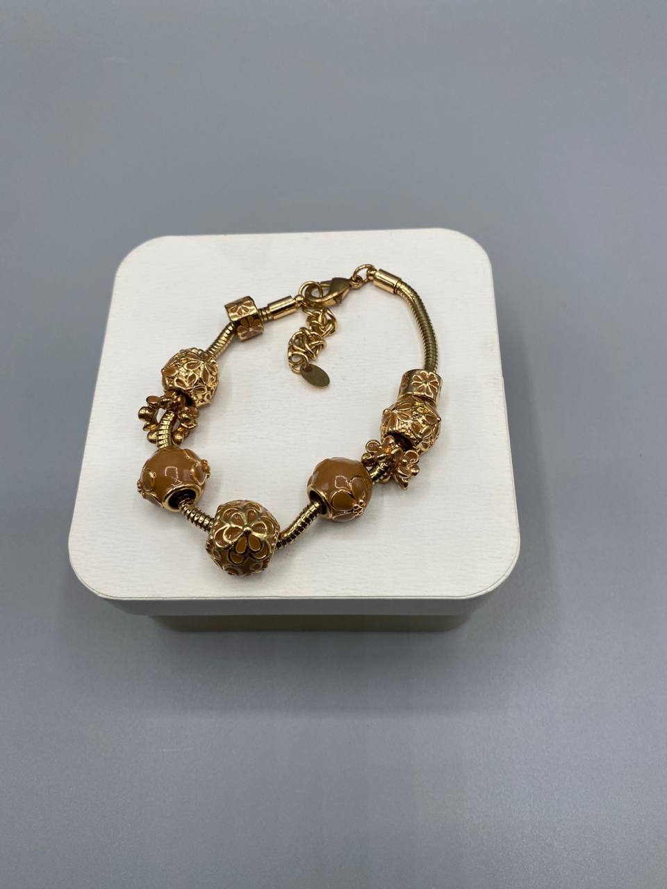 Bracelet charms doré serpentine, perles émaillées caramel et charms ajourés floraux