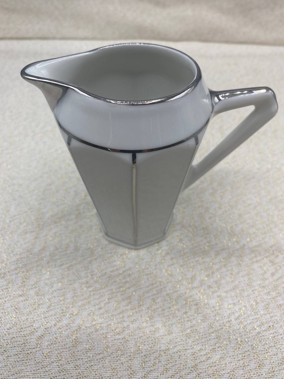 Vue de trois quarts crémier porcelaine Art Déco anse géométrique filets platine