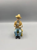 Figurine biscuit vieil homme assis chapeau paille pipe livre vue de face