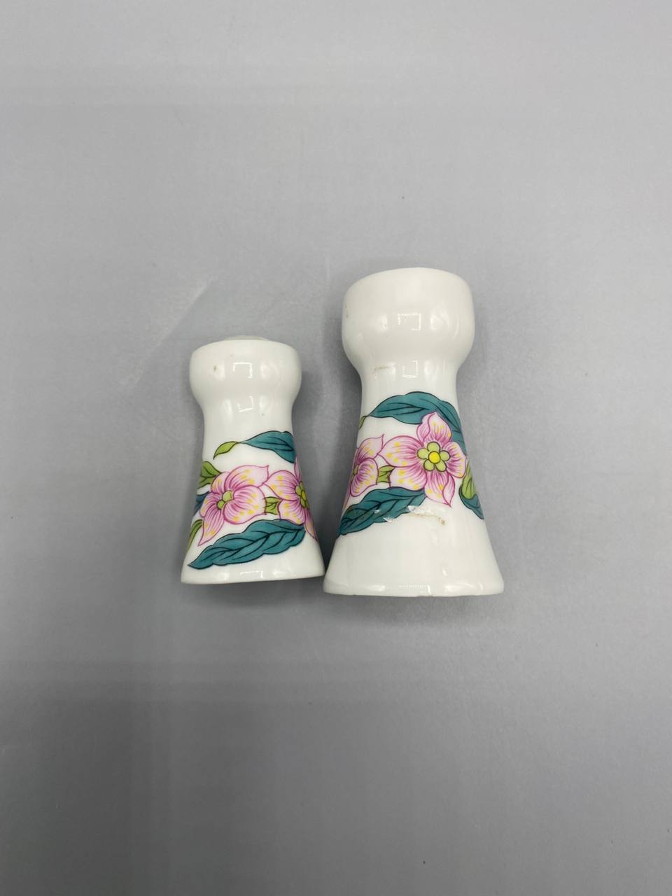 Vue de dos salière poivrière porcelaine décor floral roses feuilles vertes bouchons visibles