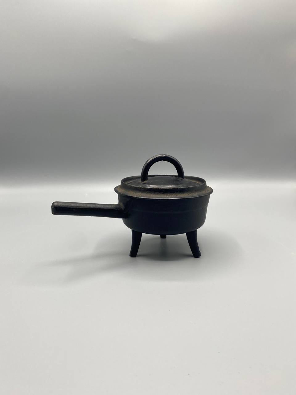 Petite cocotte tripode fonte noire manche long couvercle prise demi-anneau vue de face