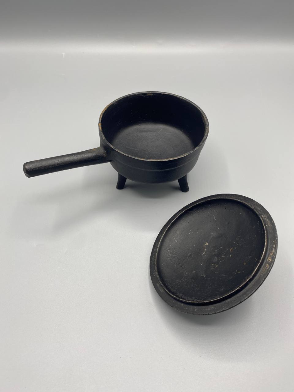 Vue de dessus cocotte tripode fonte noire ouverte intérieur brut manche horizontal