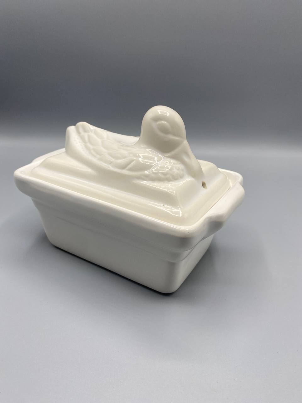 Vue de trois quarts plat terrine porcelaine blanche couvercle canard ailes déployées