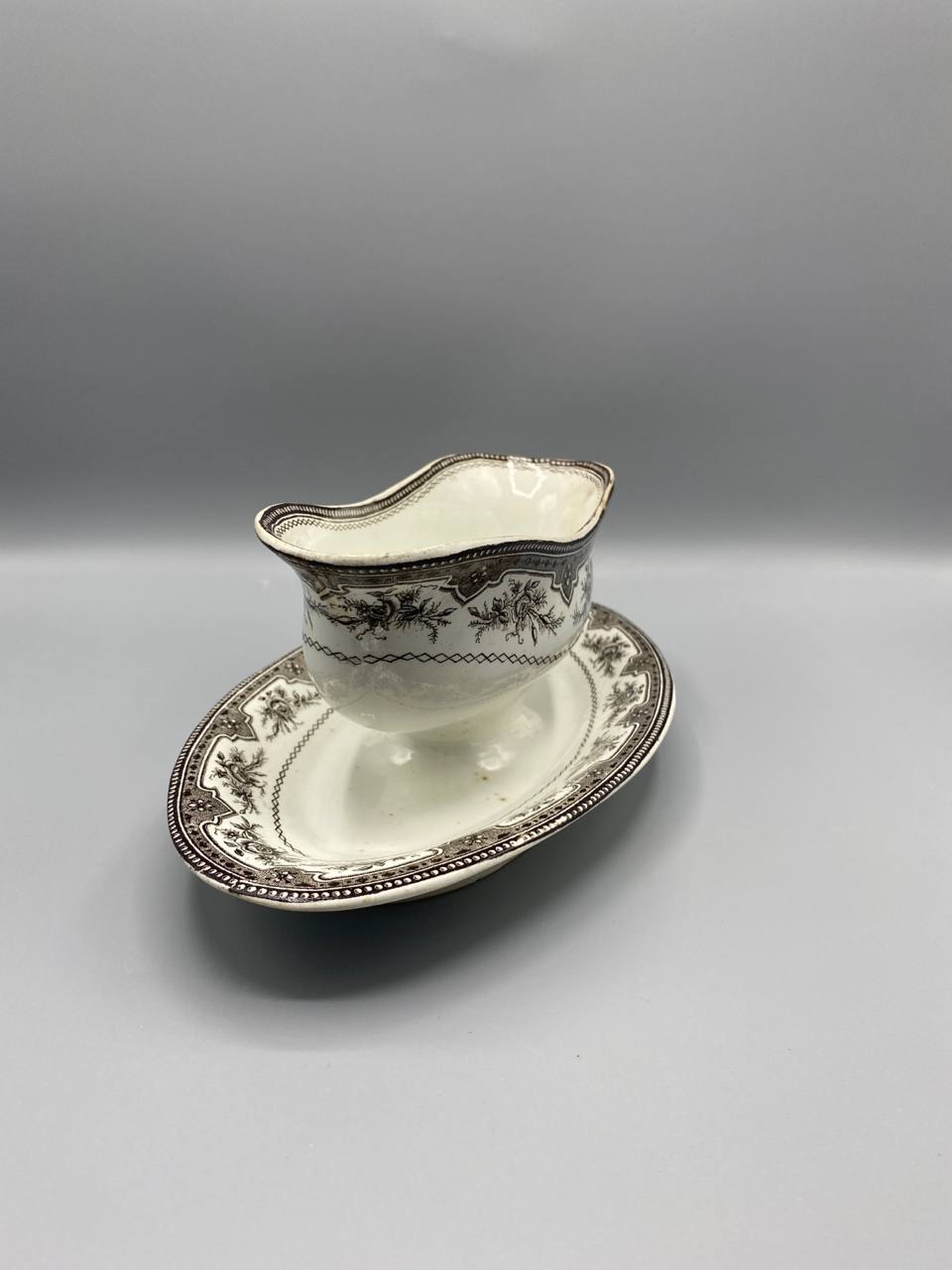 Vue de trois quarts saucière faïence fine bec verseur dormant décor guirlandes sépia