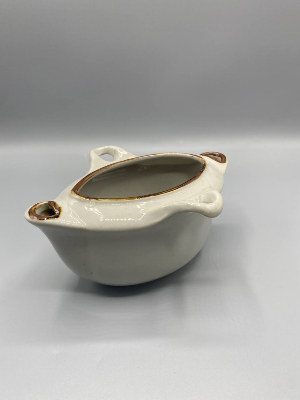 Vue de trois quarts saucière céramique blanche filet doré oreilles latérales intérieur brun tabac
