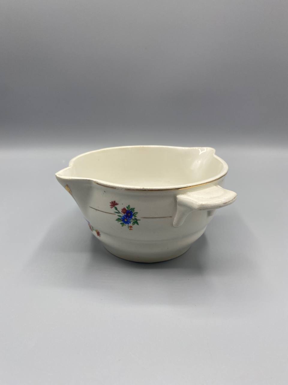 Vue de trois quarts saucière semi-porcelaine ivoire bec verseur oreilles latérales décor floral