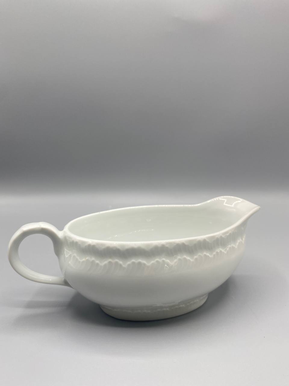 Vue de trois quarts saucière porcelaine blanche relief torsadé anse bec verseur