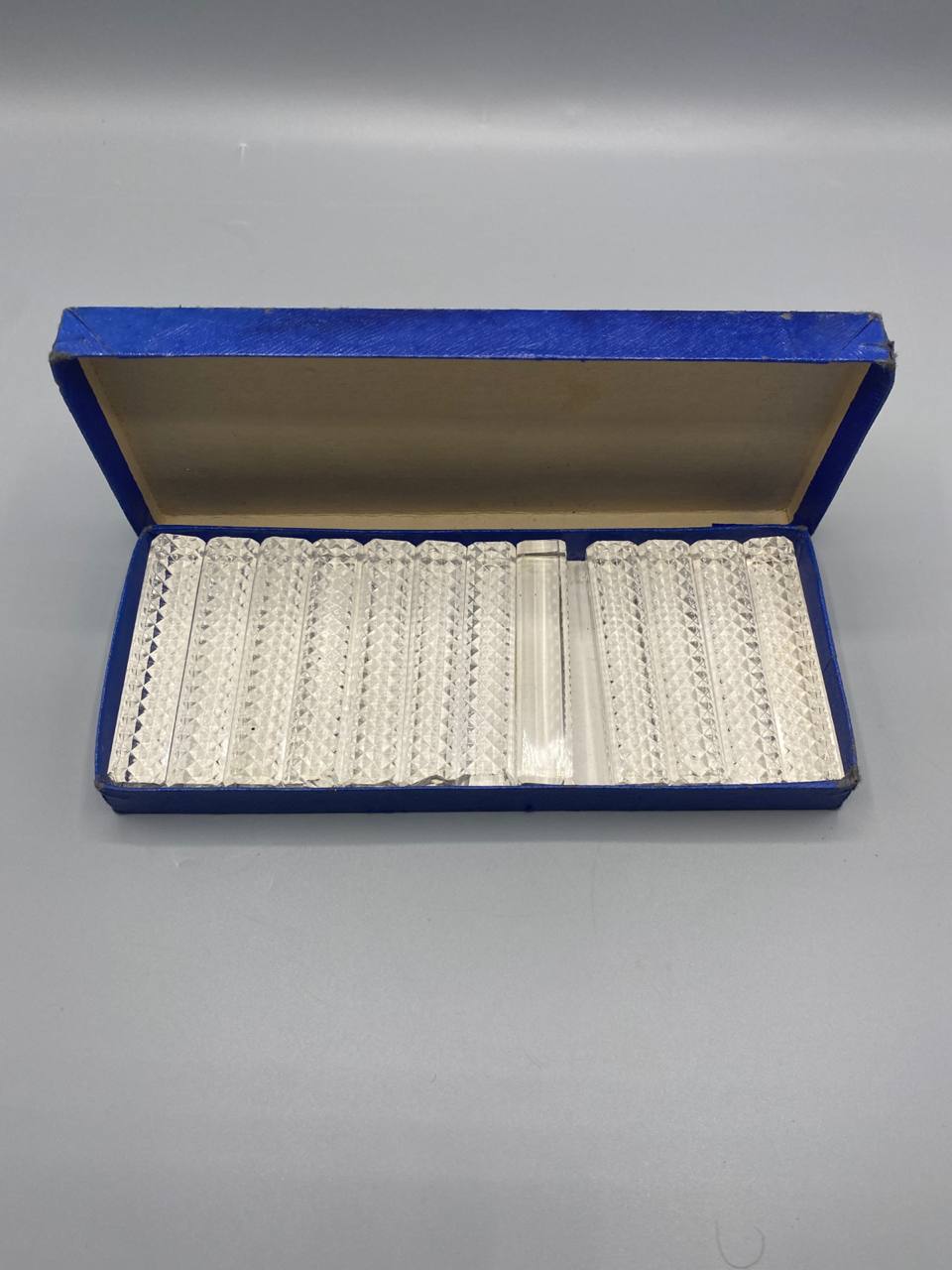 Vue de dessus boîte ouverte 12 porte-couteaux cristal taillé facettes diamant rangés dans leur écrin bleu