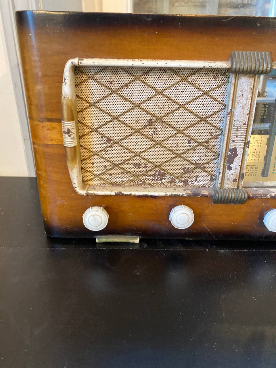 Gros plan façade radio Art Déco grille haut-parleur losangée chrome oxydé boutons bakélite blancs