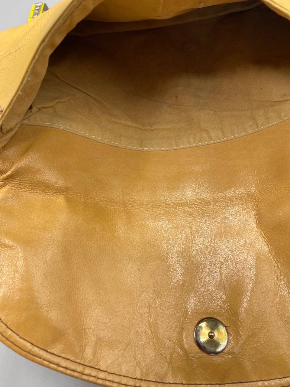 Gros plan intérieur pochette cuir miel fermeture pression dorée patine naturelle