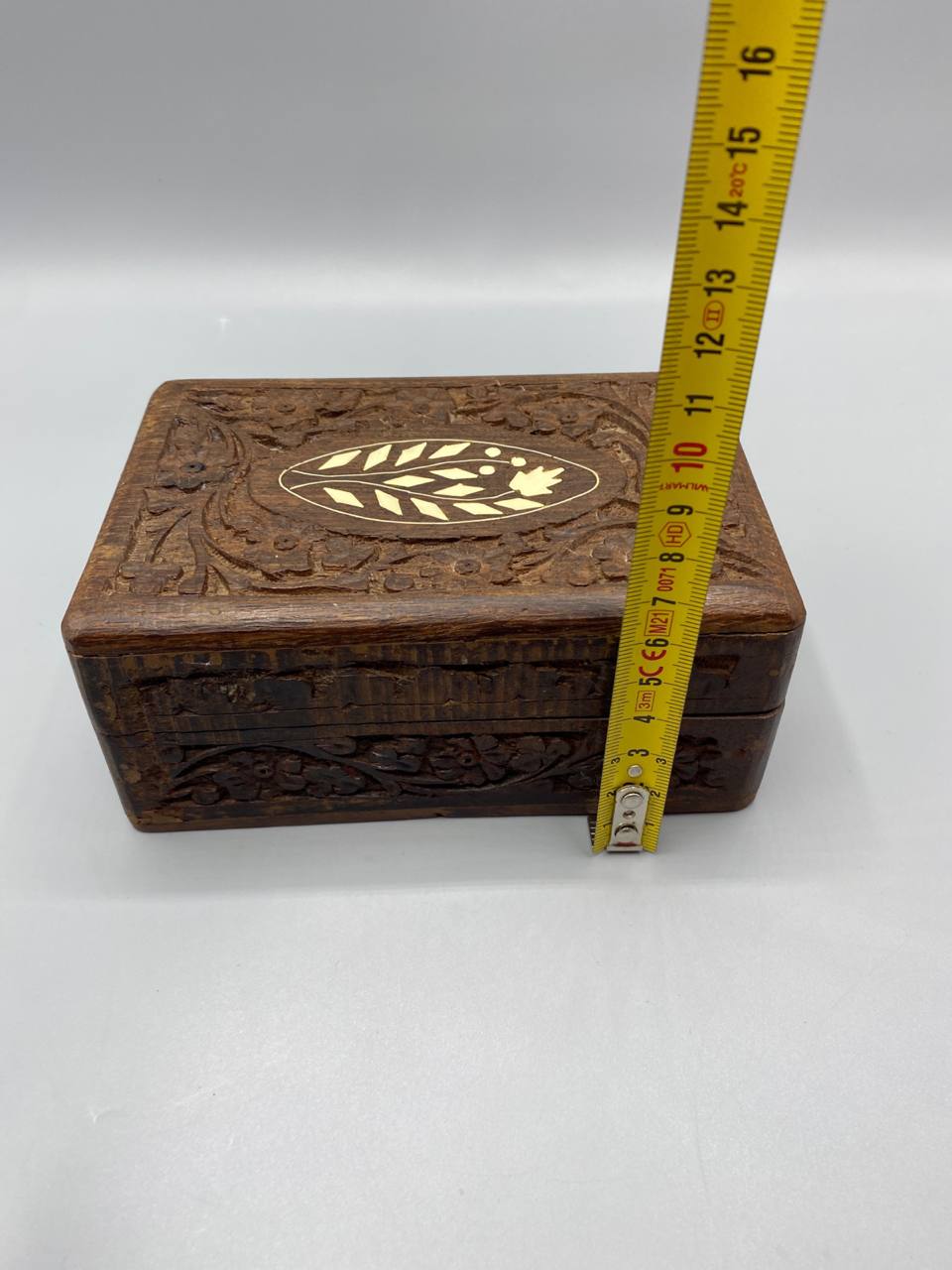 Gros plan médaillon ovale incrustation os branche feuillue stylisée fleur bois sheesham sculpté détail