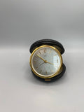 Pendulette de voyage UTI France, cadran guillouché argenté avec calendrier, étui cuir noir ouvert