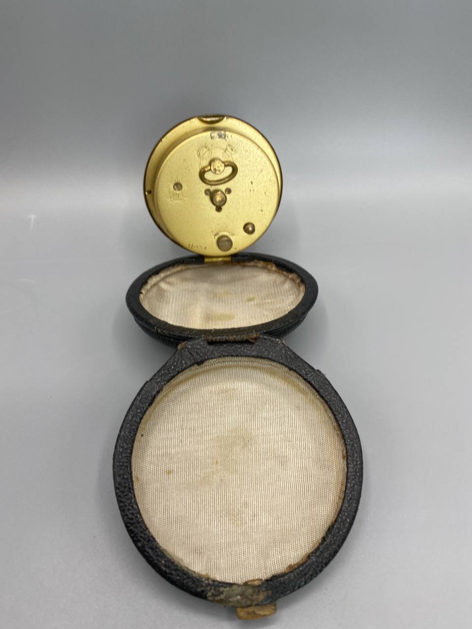 Pendulette de voyage UTI, dos du mouvement mécanique doré, étui cuir ouvert intérieur satiné