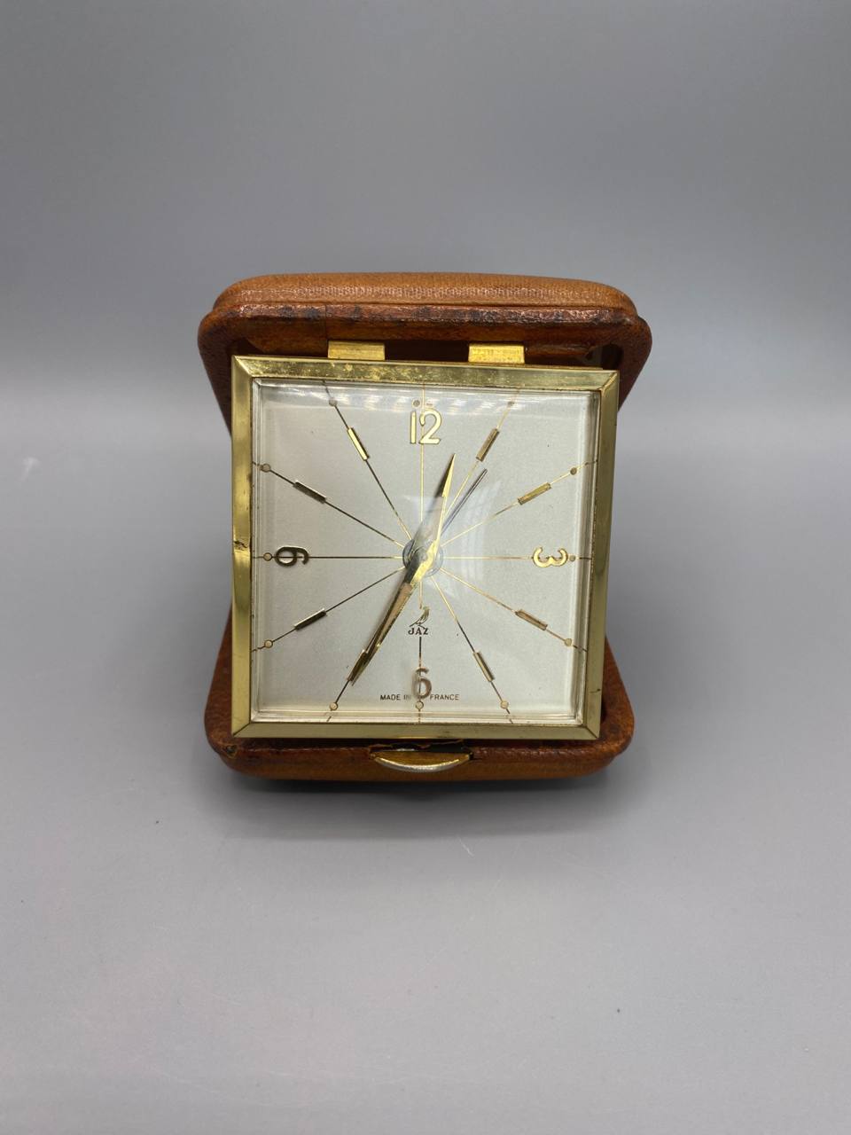 Pendulette de voyage JAZ Made in France, cadran carré blanc index dorés rayonnants, étui cuir camel ouvert