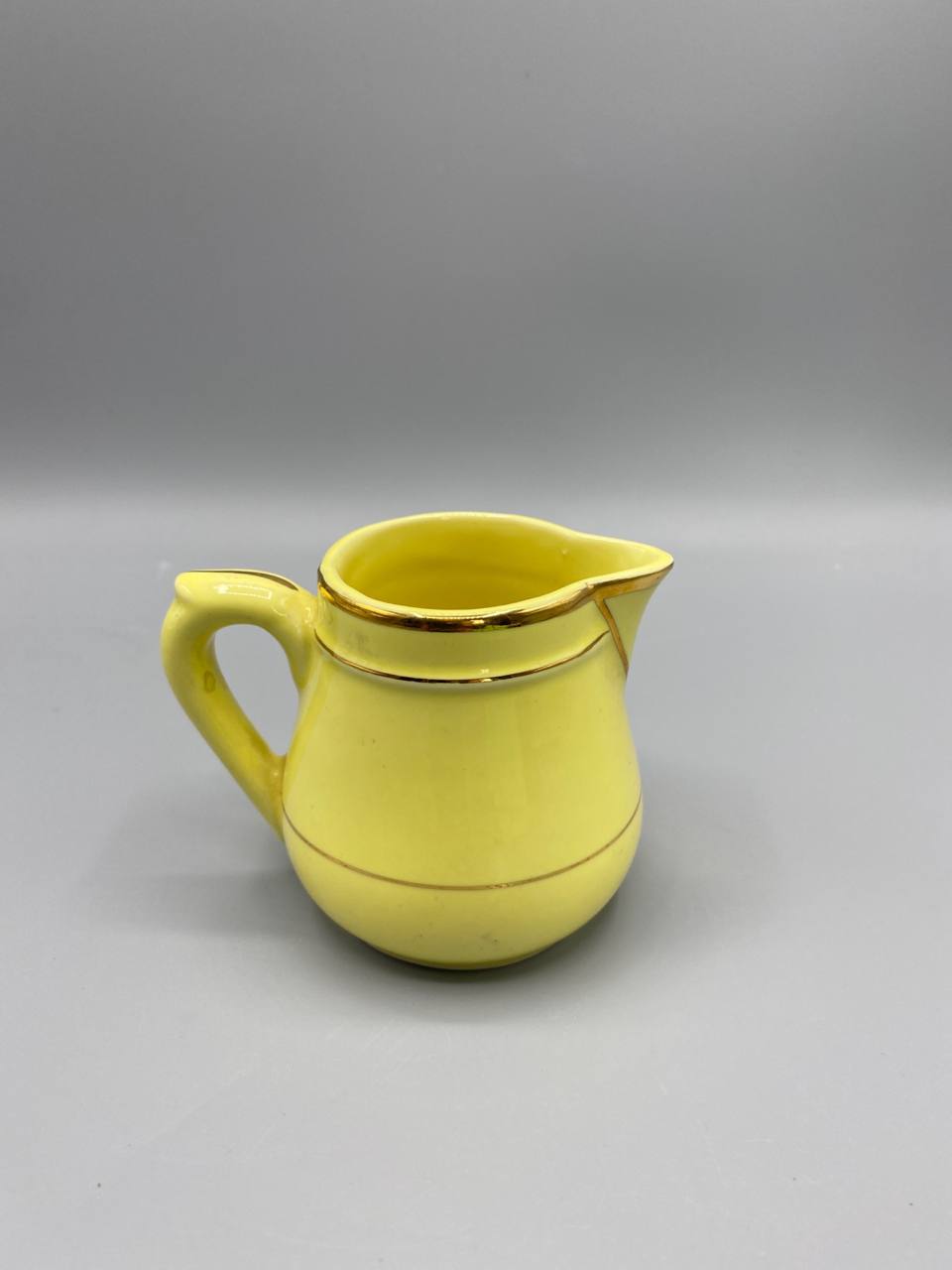 Petite crémière en faïence jaune vif, filets dorés, vue de face