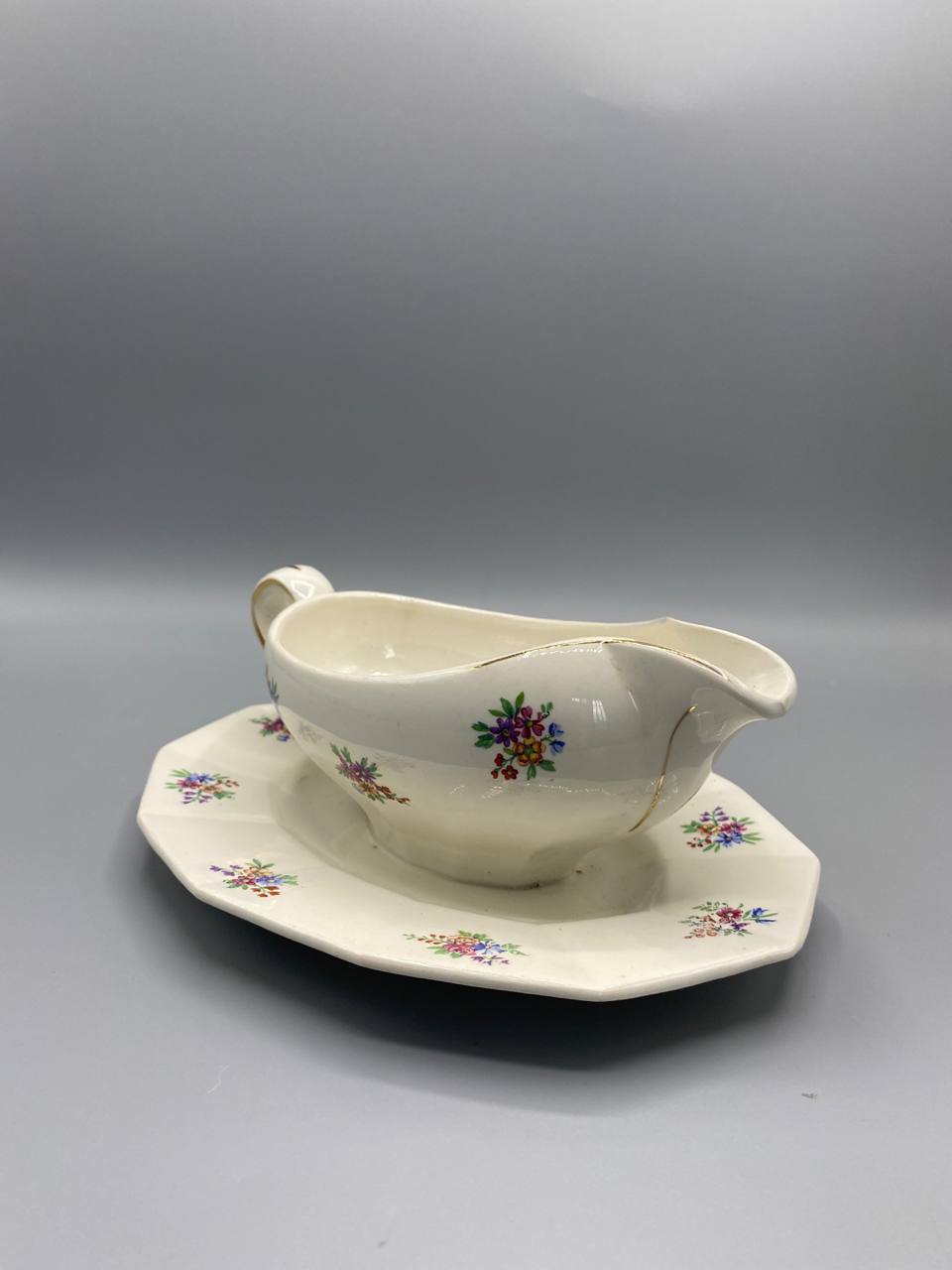 Saucière Porcelor Ceranord vue de trois quarts, anse annulaire dorée, bec verseur en pointe fine