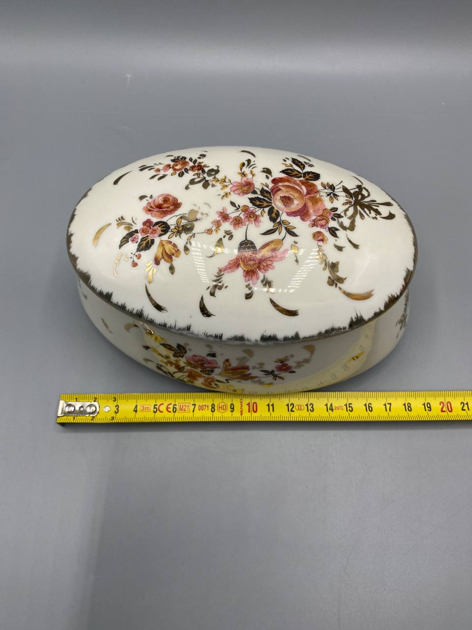 Bonbonnière ovale vue de dessus avec mètre ruban, largeur environ 14 cm, décor couvercle