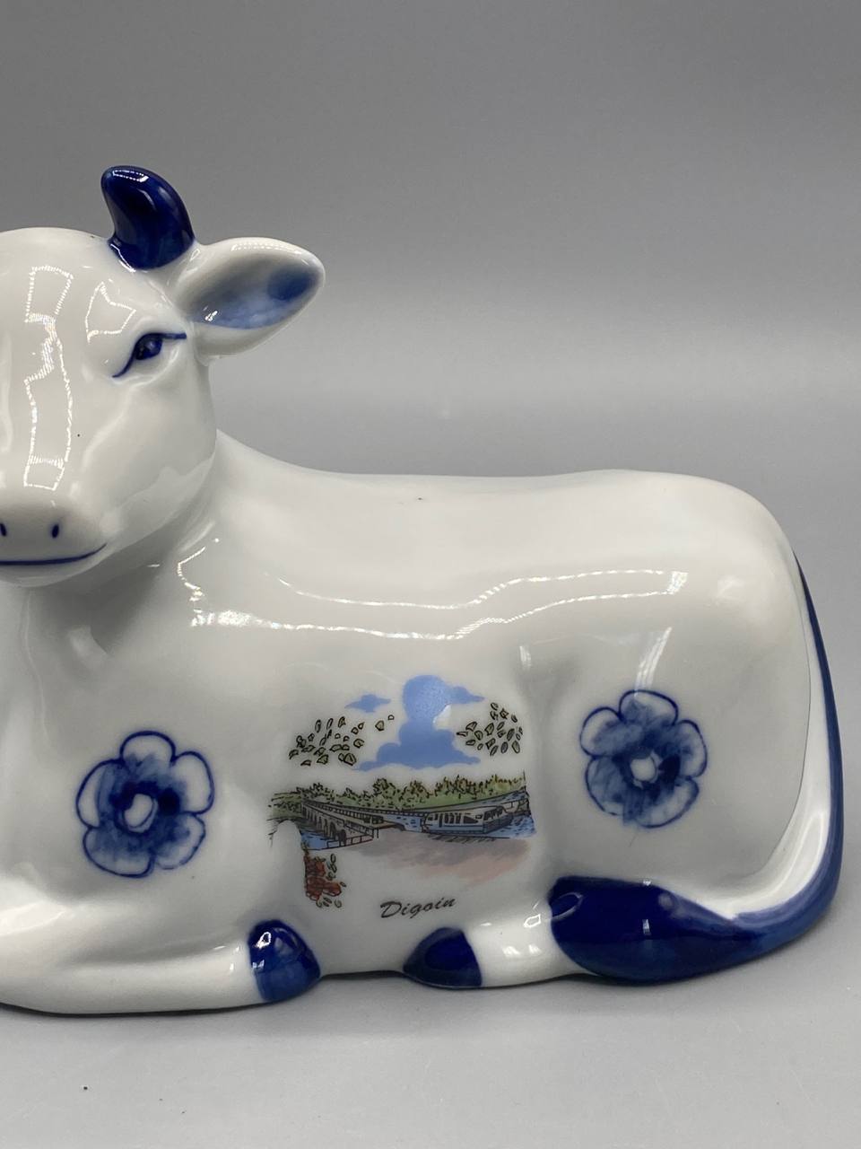 Figurine vache, vue de dos, queue émaillée bleu cobalt relevée, fleur bleue sur la croupe