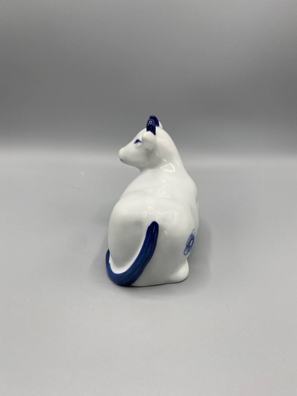 Figurine vache, vue de trois quarts arrière, sabots bleus, forme sculptée, fond ouvert visible