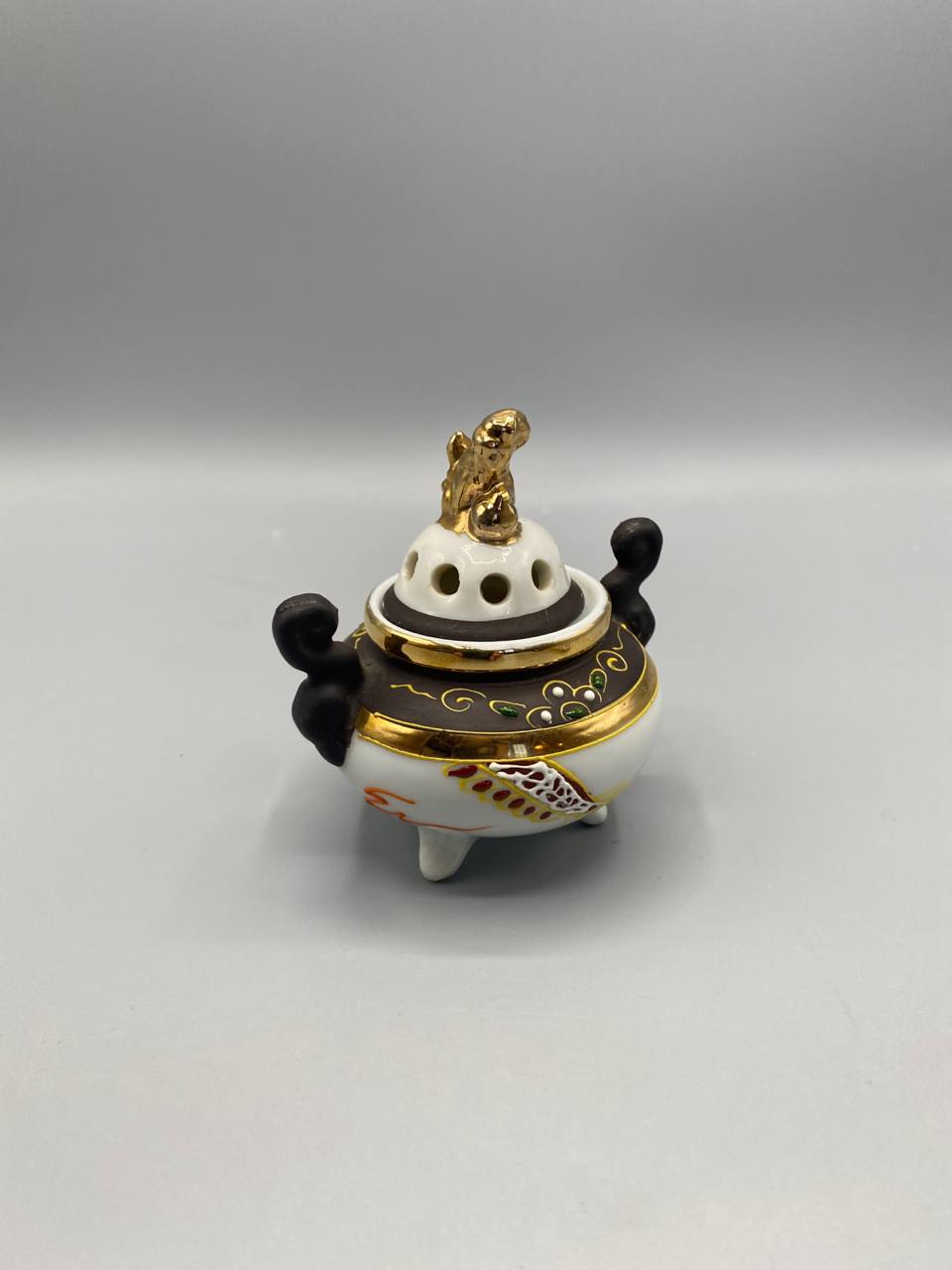 Brûle-parfum japonais, vue de trois quarts, couvercle ajouré, frise brune dorée, motifs floraux polychromes sur fond blanc
