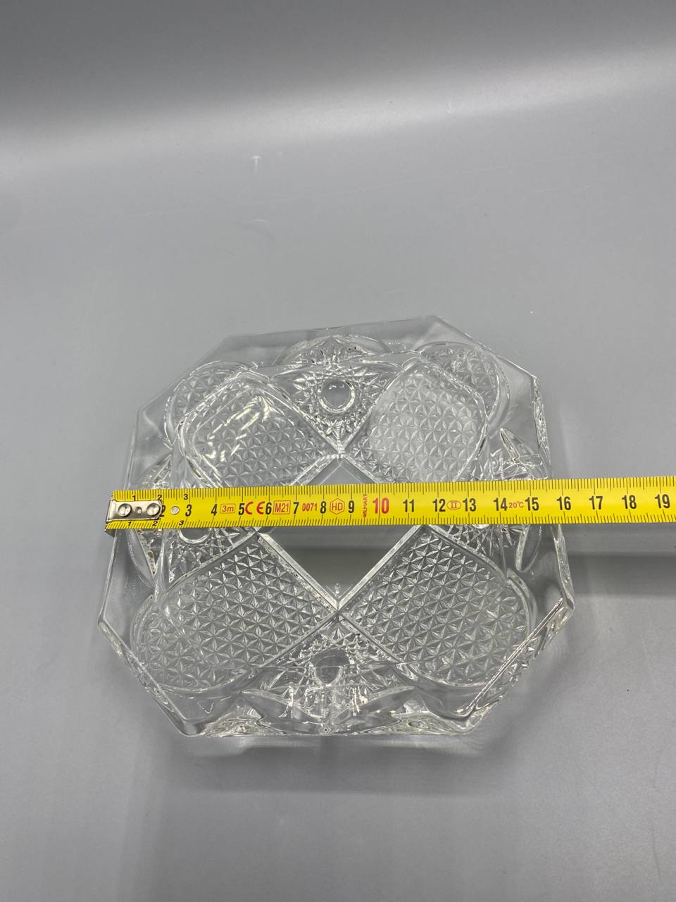 Cendrier cristal avec mètre ruban, côté environ 15 cm, vue de dessus, taille moulée détaillée visible