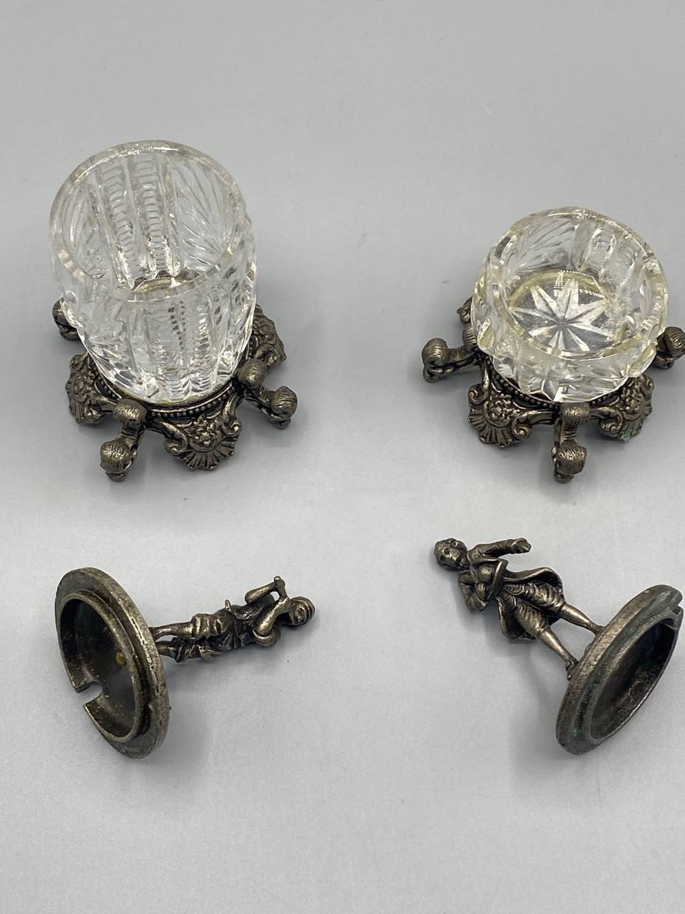 Corps des moutardiers retournés, fond en cristal taillé étoile, socles métal argenté à décor acanthe, couvercles démontés avec figurines