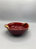 Coupe céramique rouge sang de boeuf, vue de trois quarts, deux anses sculptées à finition dorée, forme hémisphérique aplatie