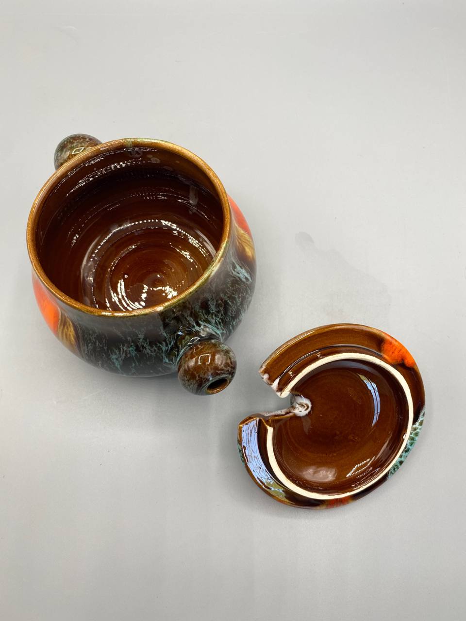 Pot Vallauris ouvert, intérieur émaillé brun caramel brillant, couvercle retourné montrant l'ébréchure sur le bord