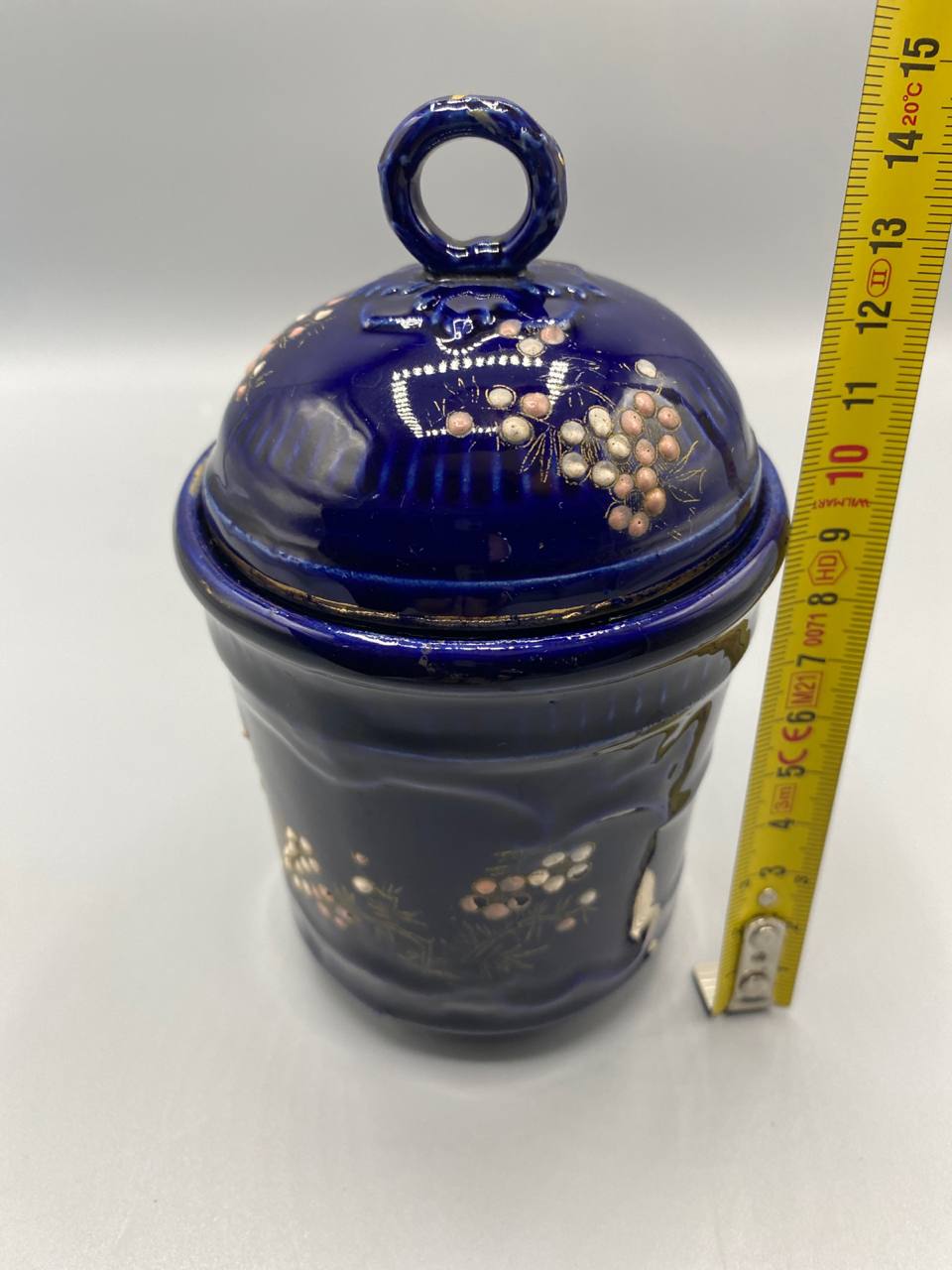 Pot couvert fermé avec mètre ruban, hauteur totale avec couvercle environ 14 cm, vue de profil, décor baies et feuillage doré visible