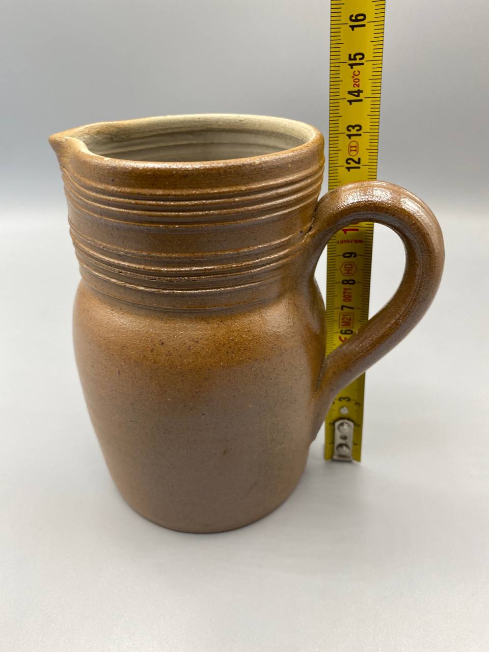 Pichet grès du Berry avec mètre ruban, hauteur environ 13 cm, vue de profil, glaçure brun ambré et gorges tournées