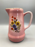 Pichet faïence rose, face principale, bouquet de fleurs polychrome rouge jaune bleu sur fond blanc réservé, filet doré au col et à la base