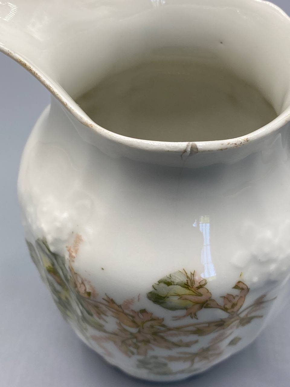 Pot à lait porcelaine, vue de dessus, intérieur blanc ivoire, fêle ancien au niveau du col visible, bec verseur évasé
