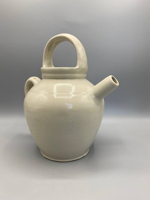 Gargoulette grès crème, vue de profil côté bec, bec tubulaire cylindrique horizontal, panse ovoïde renflée, émail crème brillant uniforme