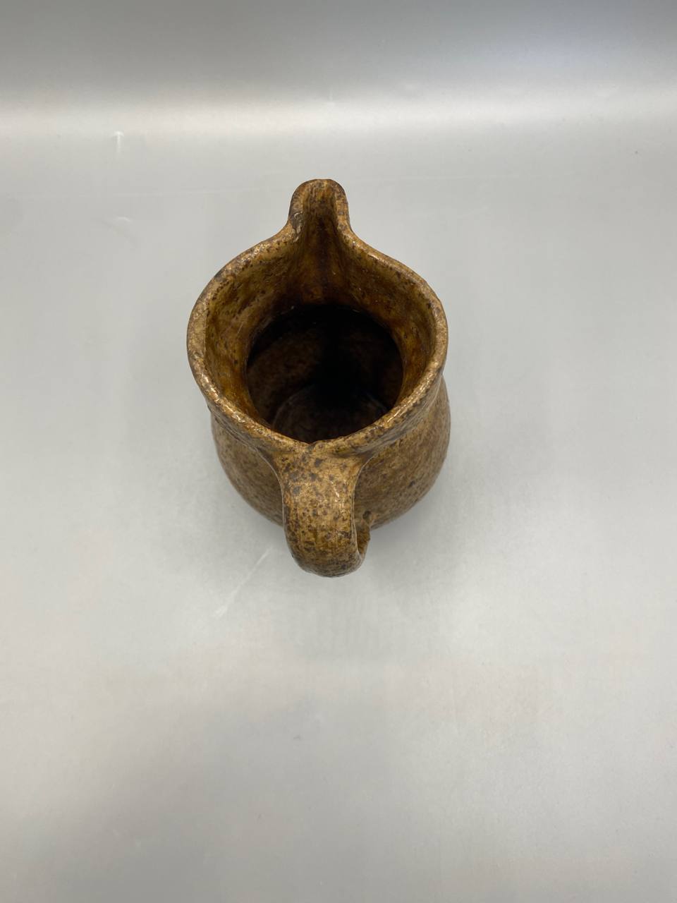 Pichet terre cuite vu de dessus, intérieur vernissé brun foncé brillant avec traces d'usage ancien, bec verseur pincé en V très prononcé