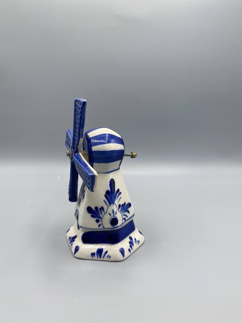 Moulin hollandais Delft bleu, vue de trois quarts arrière, décor floral en feuilles et palmettes bleues, axe métallique des ailes visible, base hexagonale