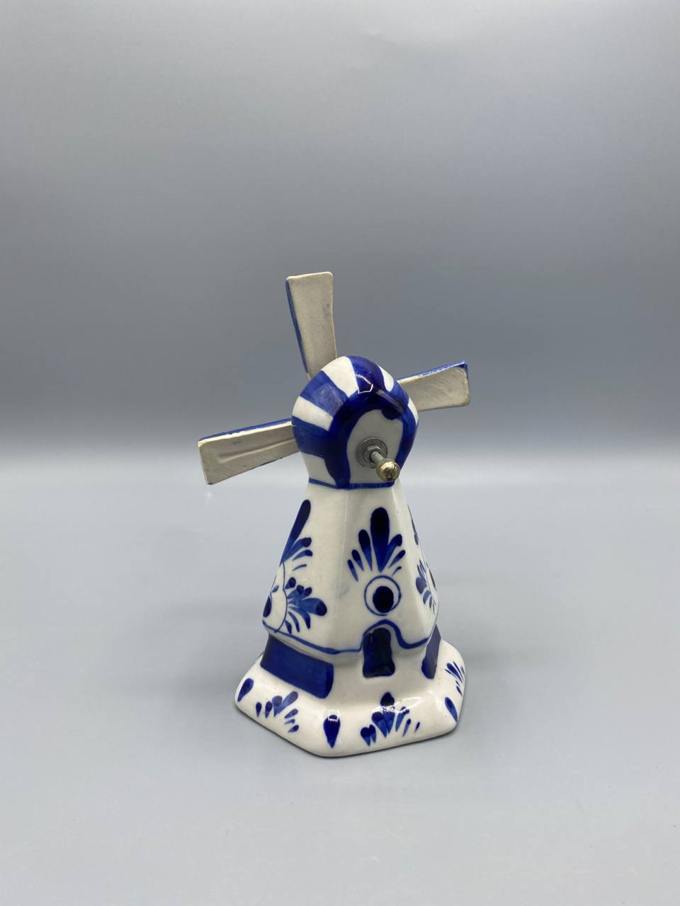Moulin hollandais Delft bleu, vue de trois quarts avant, ailes en croix avec décor quadrillé en relief, tête du moulin rayée bleu et blanc, base hexagonale