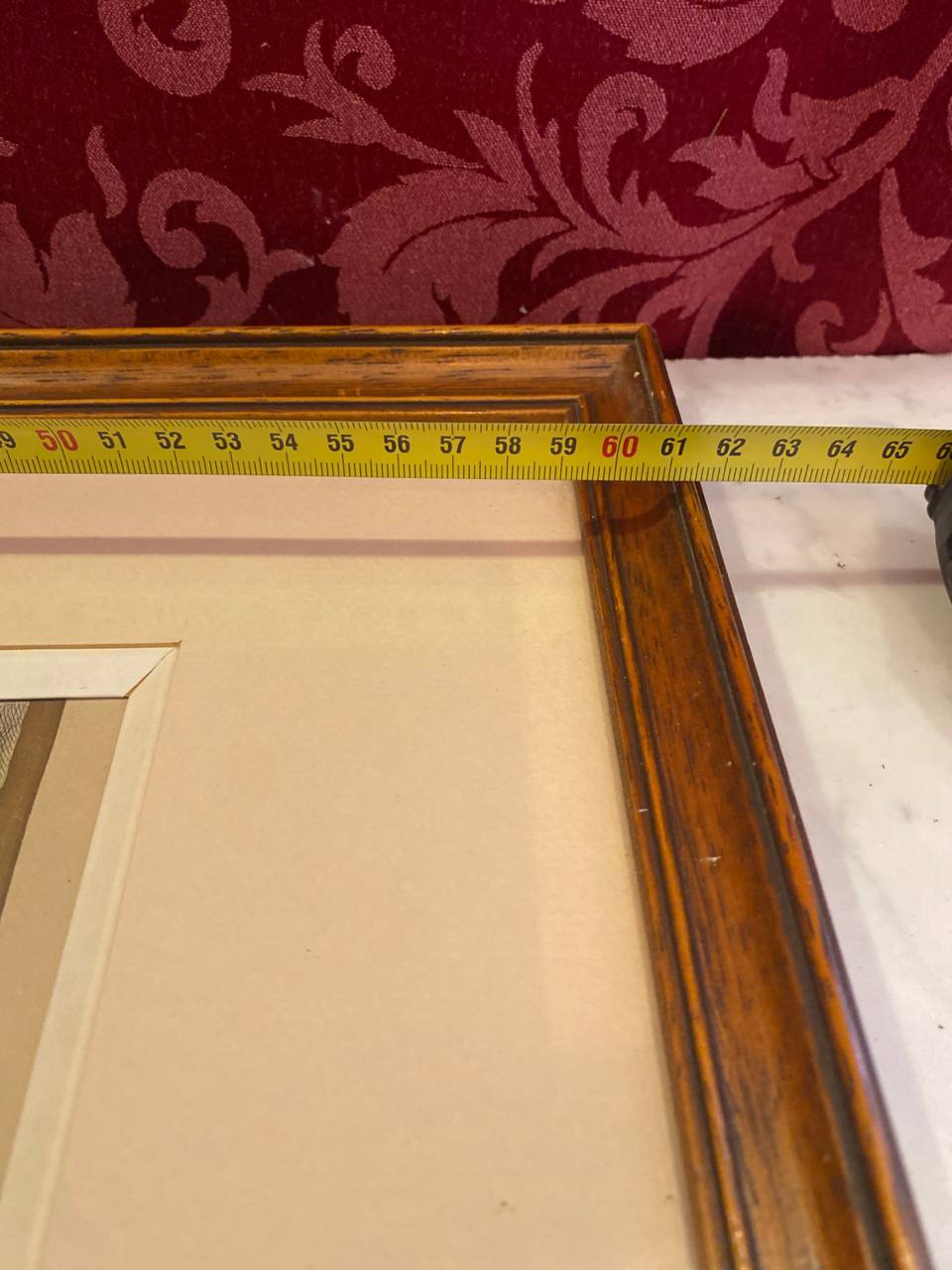 Mesure de la largeur du cadre avec mètre ruban, environ 60 cm, angle supérieur du cadre bois patiné à filet doré