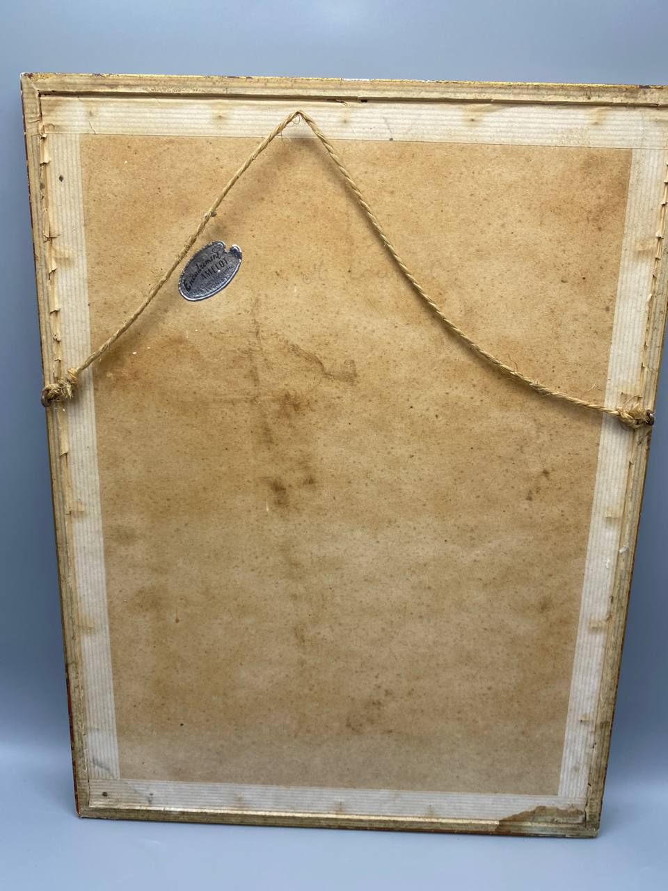 Dos de la reproduction encadrée, carton kraft avec corde de suspension en jute, étiquette ovale d'éditeur au dos, cadre doré visible sur les bords