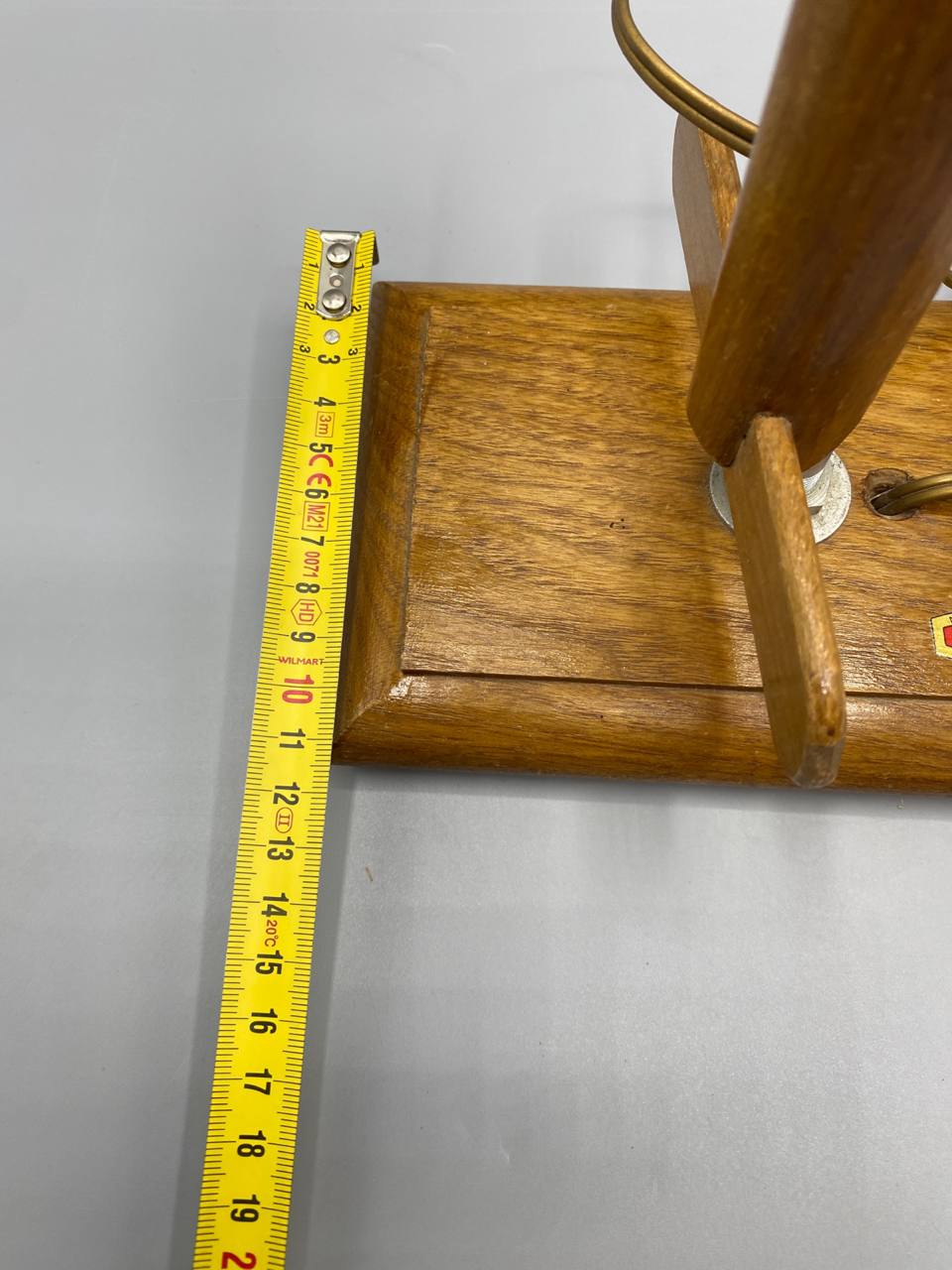 Détail de la tête chauffante chromée du fer BABETH, forme en pointe de projectile vue de profil, bras articulé en bois de chêne, cordon tressé doré