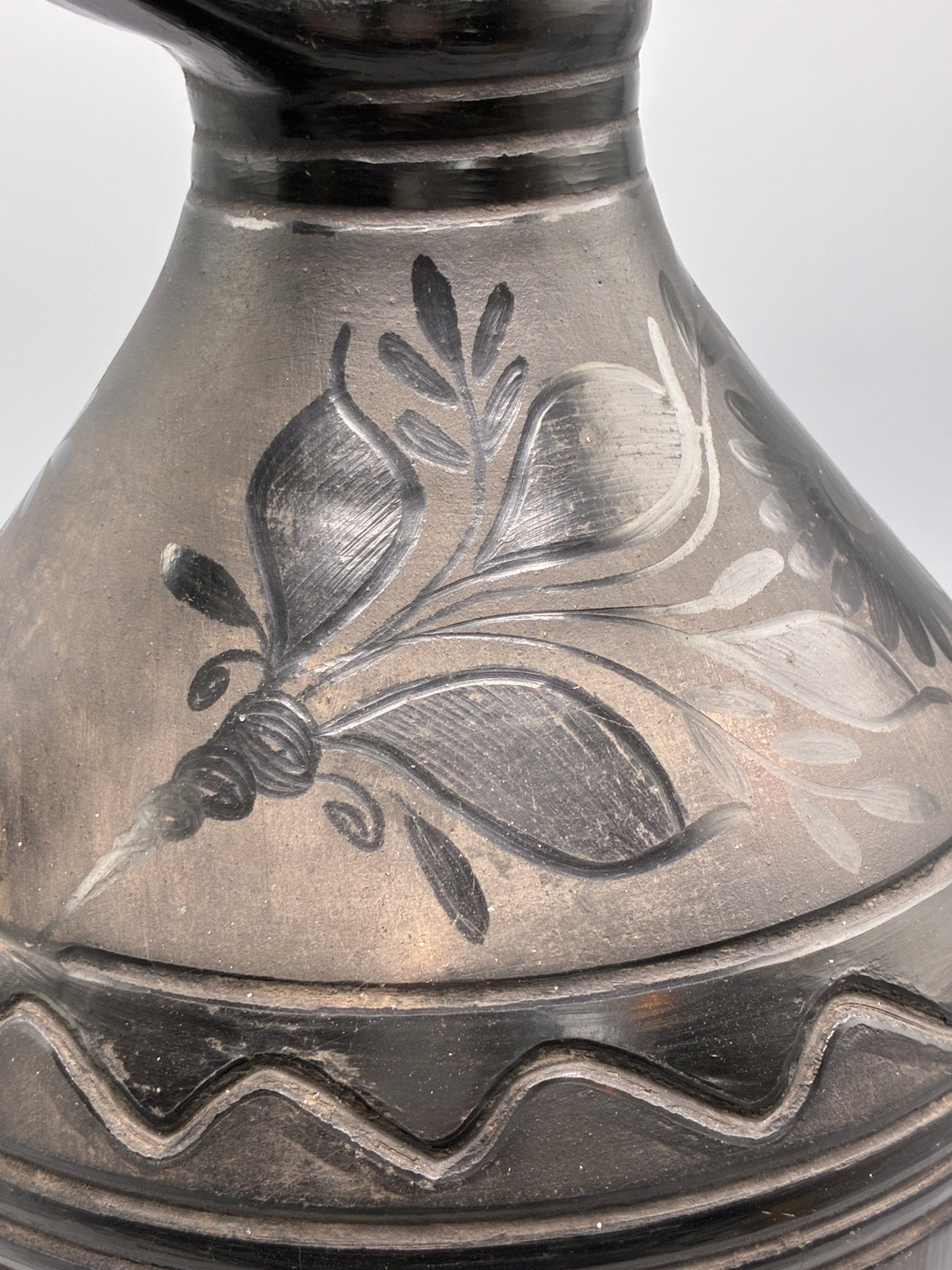 Détail du décor floral aux reflets argentés sur la céramique noire