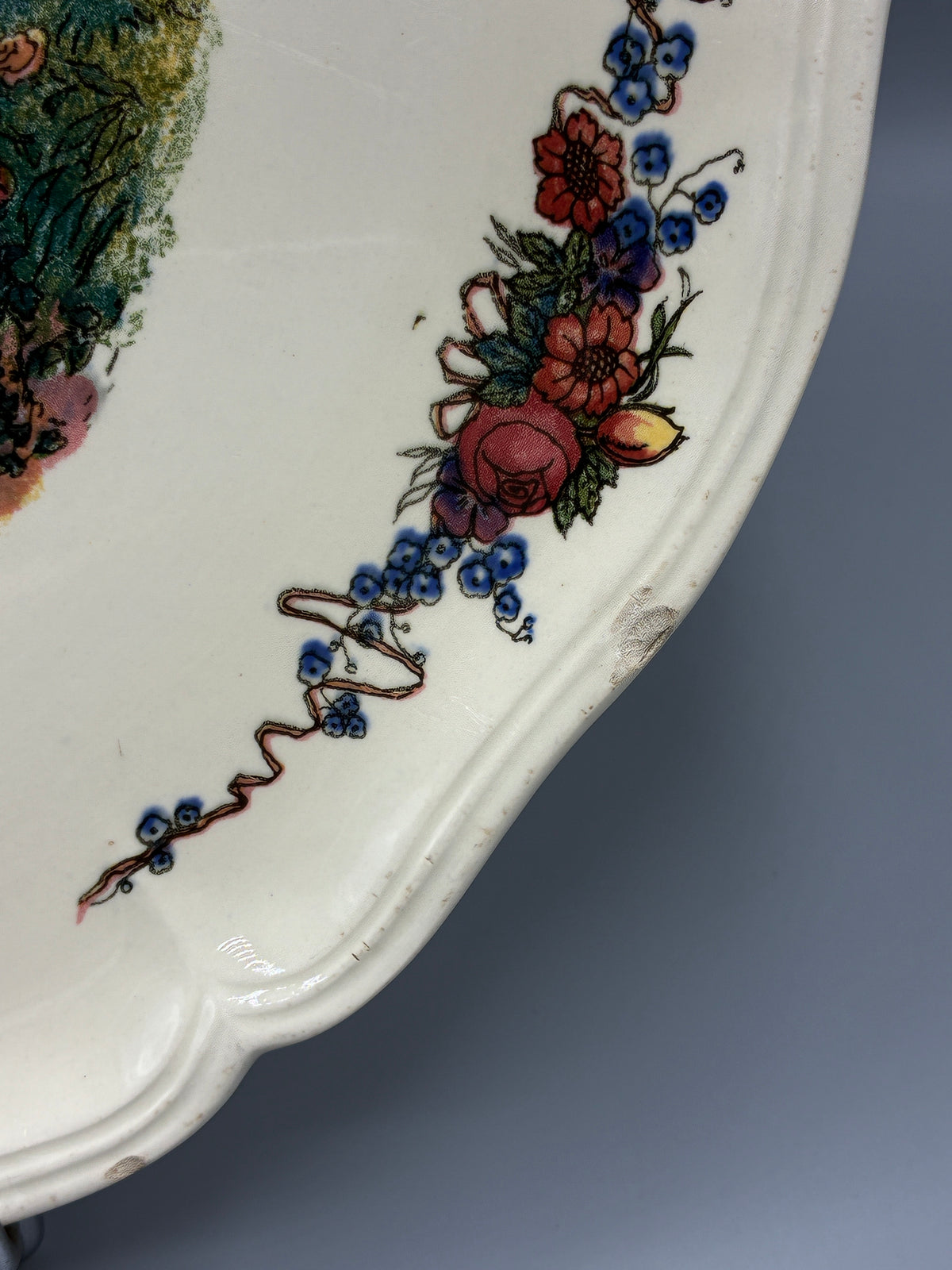 Détail des ébréchures sur le pourtour fleuri du plat