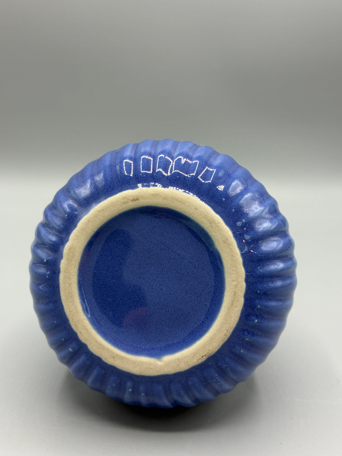 Dessous de la lampe Berger en céramique bleue avec marques peintes en blanc sur l’émail