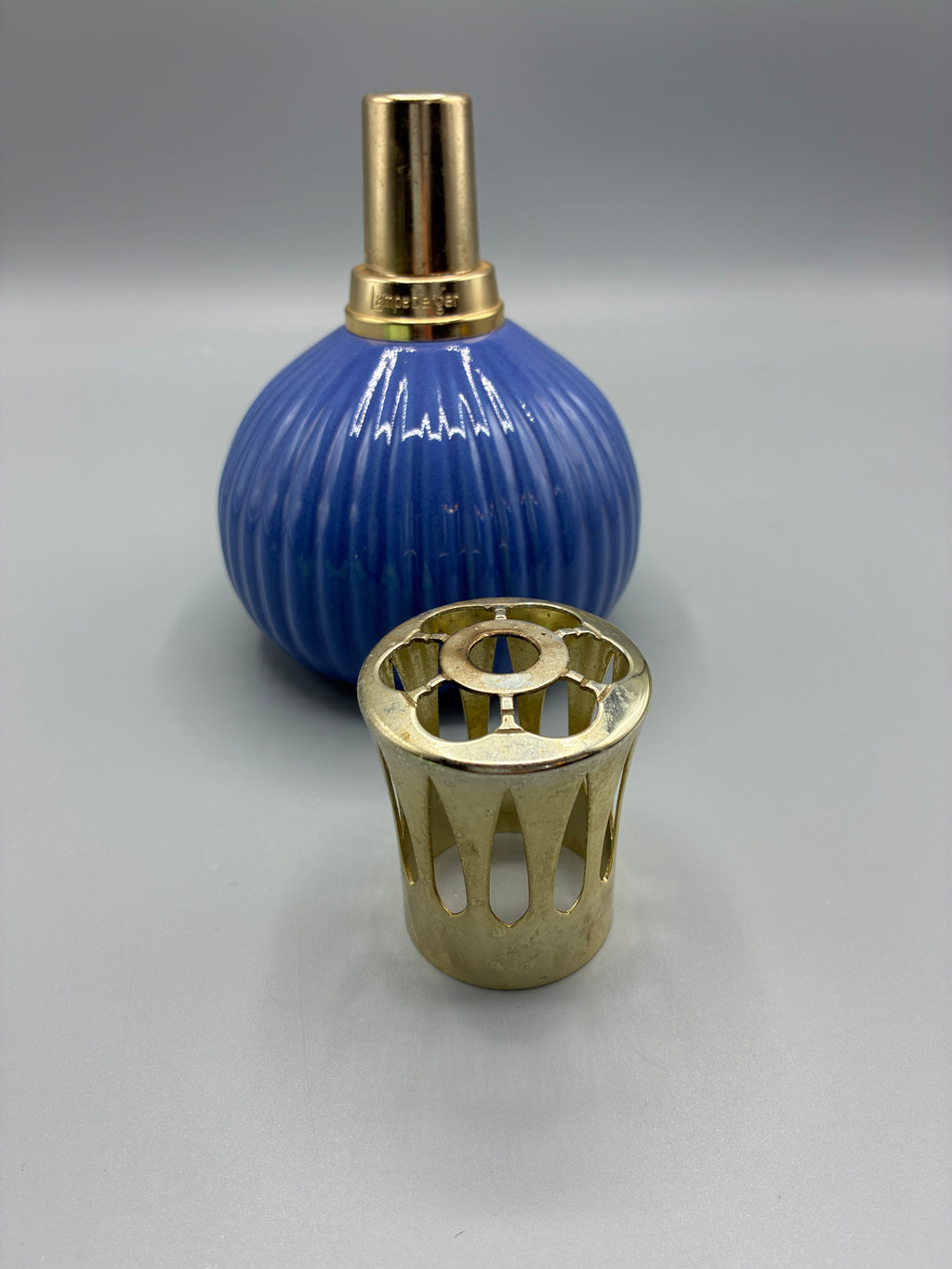 Lampe Berger en céramique bleu cobalt avec sa couronne de protection ajourée dorée déposée à côté