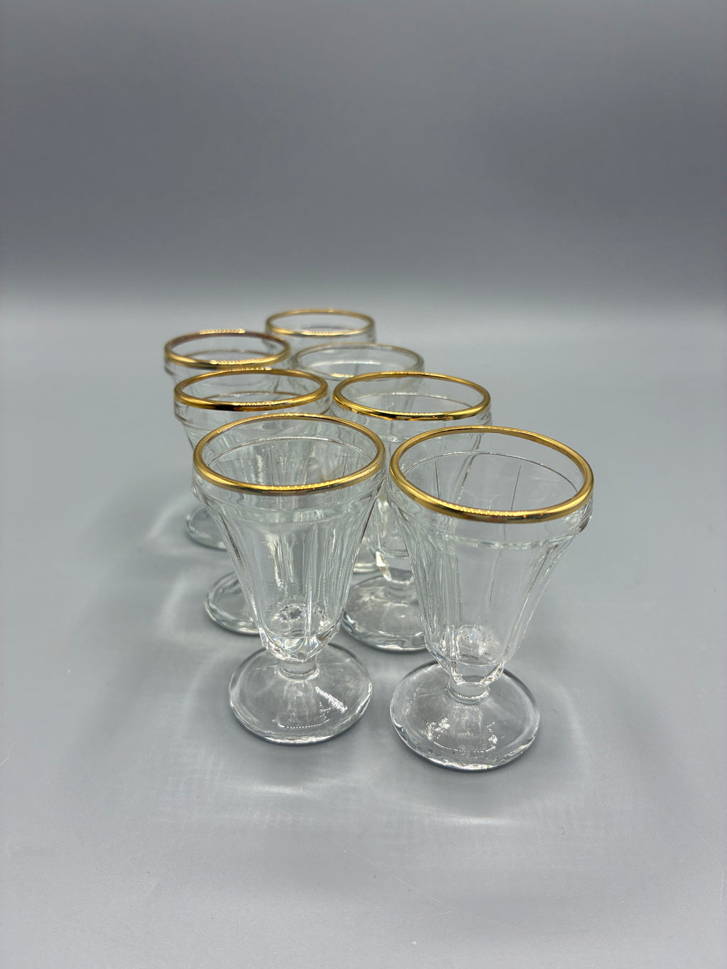 Ensemble de sept verres à liqueur facettés en verre transparent à bord doré