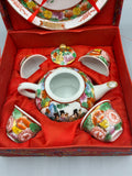 Service à saké en porcelaine polychrome avec verseuse, quatre coupelles et assiette dans son coffret rouge ouvert