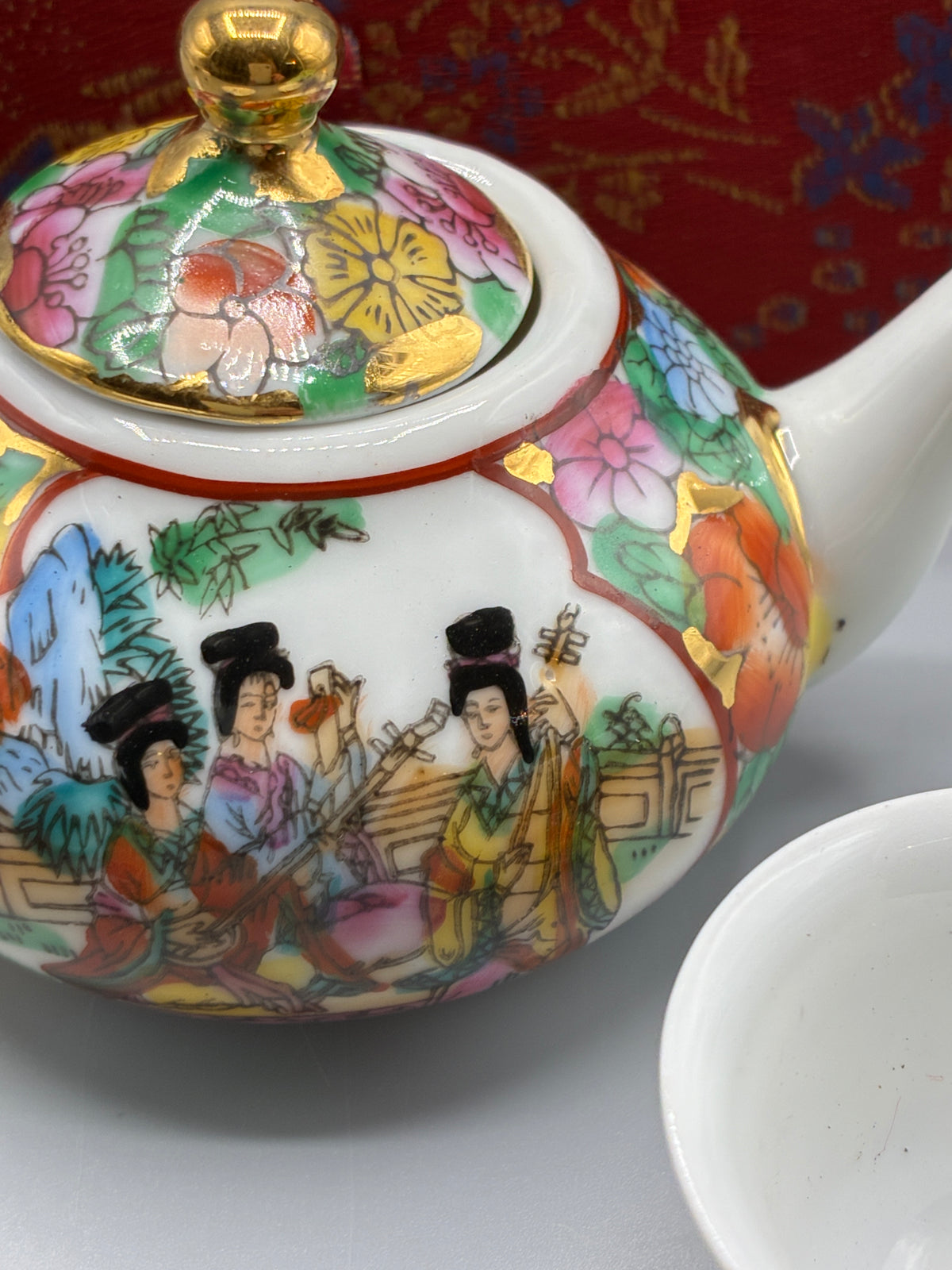 Assiette à décor de musiciennes et frise florale maintenue par les rubans du coffret