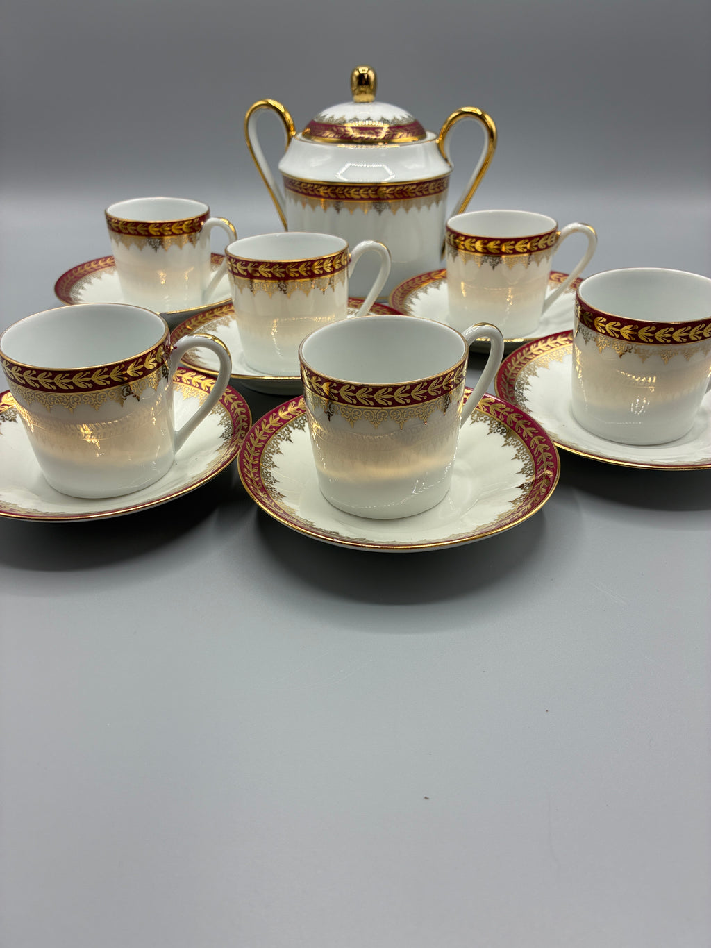 Sucrier couvert à deux anses dorées entouré des tasses et soucoupes assorties