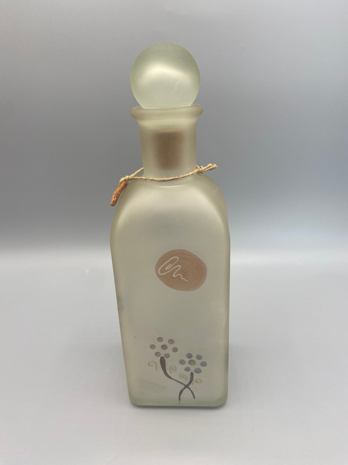 Flacon carafe, face avec signature rose poudre et motifs floraux en bas