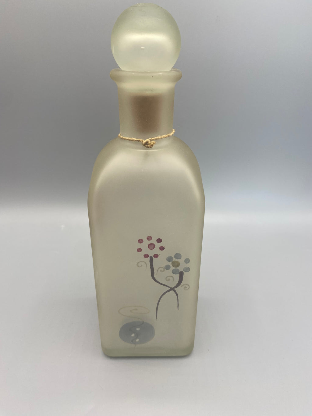 Troisième face du flacon, motifs floraux gris-brun sur verre dépoli