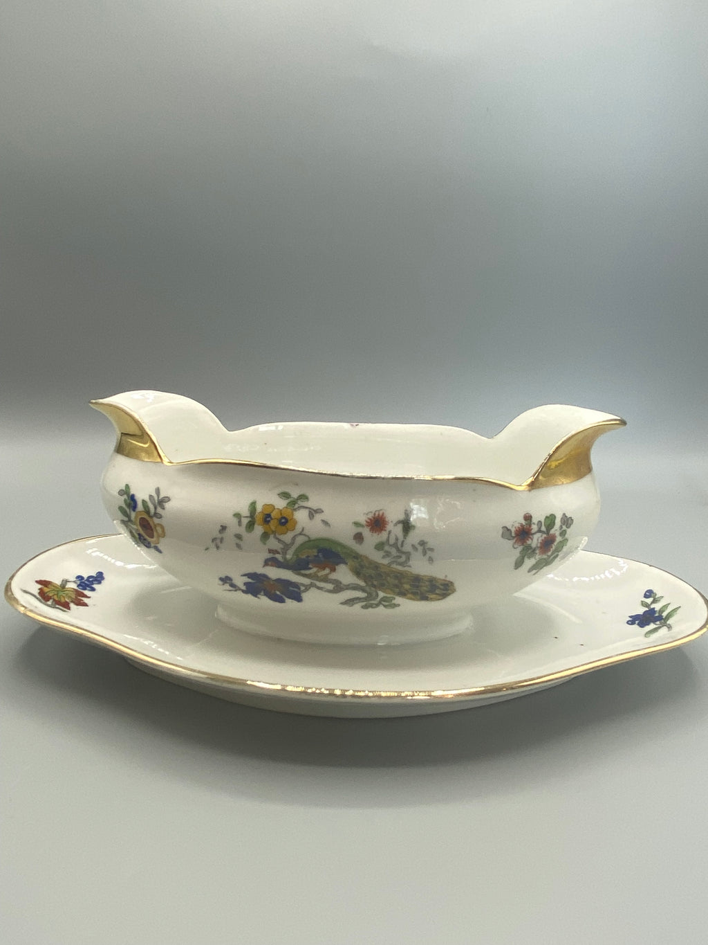 Saucière porcelaine Limoges Charles Field Haviland GDA, décor paon et fleurs polychromes, vue de face avec présentoir
